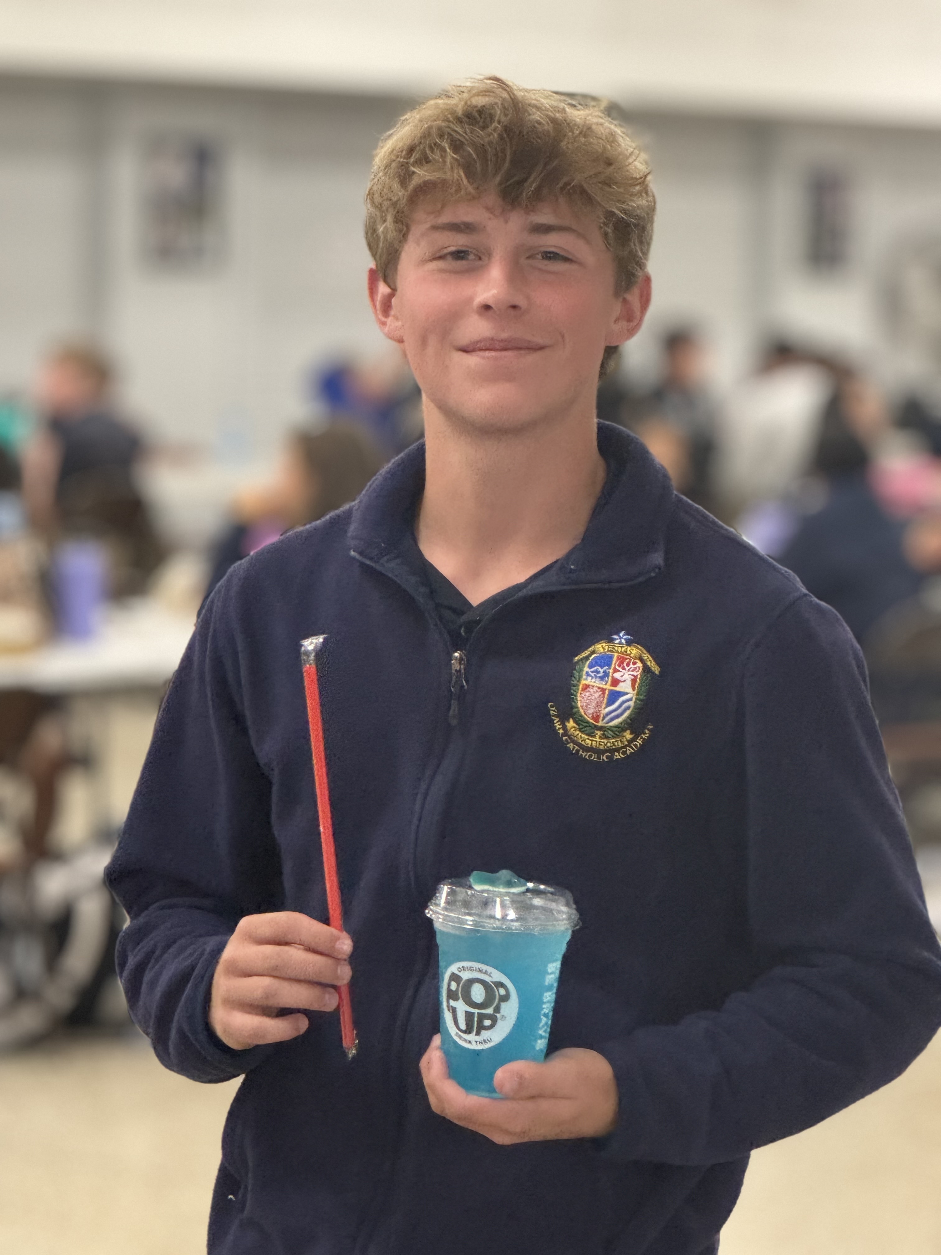 Happy Ozark Catholic Academy student with PopUp beverage, demonstrating customer satisfaction with the student-run business program
