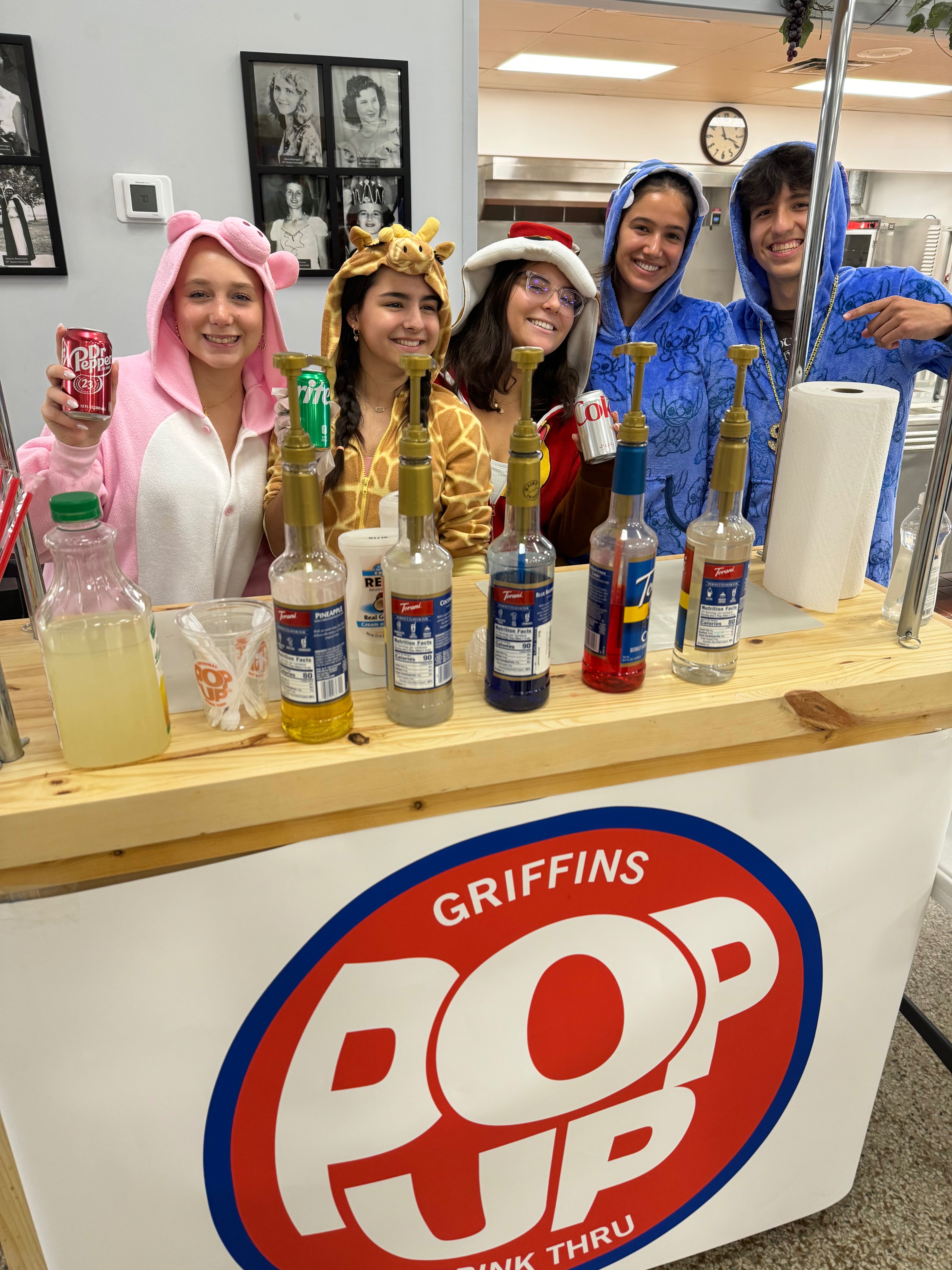 Ozark Catholic Academy students operating their Griffins Pop business, wearing fun costumes and serving beverages at their PopUp kiosk